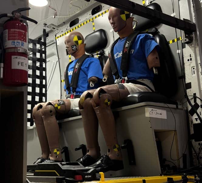 Two instrumented crash test dummies secured with harnesses on the bench seat