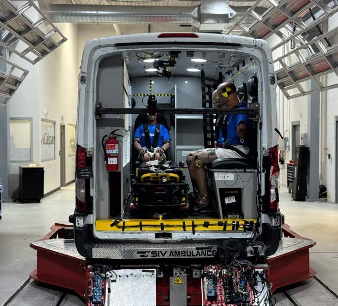 Crash test dummies seated in the patient compartment, viewed through the rear doors
